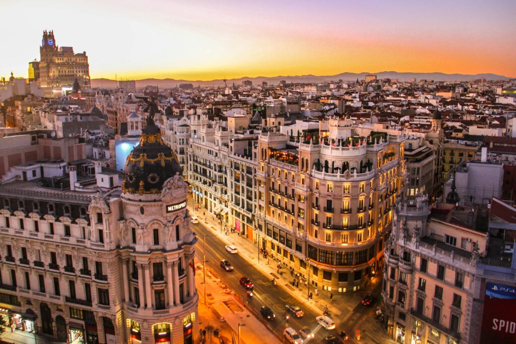 A sunset view of Gran Via in Madrid, with historic buildings and city lights starting to glow.