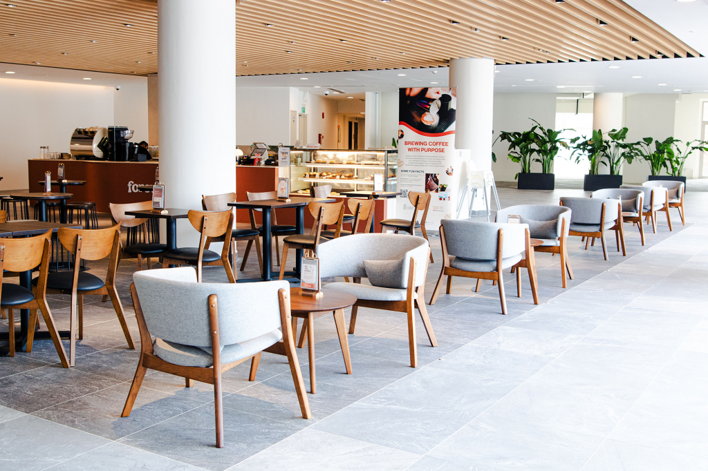 Spacious open lounge seating area at Foreword Coffee in Singapore with light wood ceiling, pale armchairs and a cafe counter