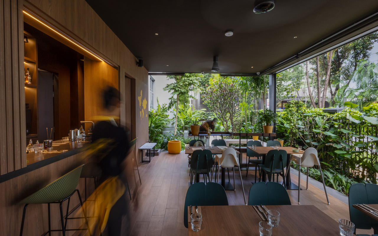 Bettr Barista cafe on Havelock Road, Singapore, with a wood bar, green chairs and an open dining area opening onto lush greenery
