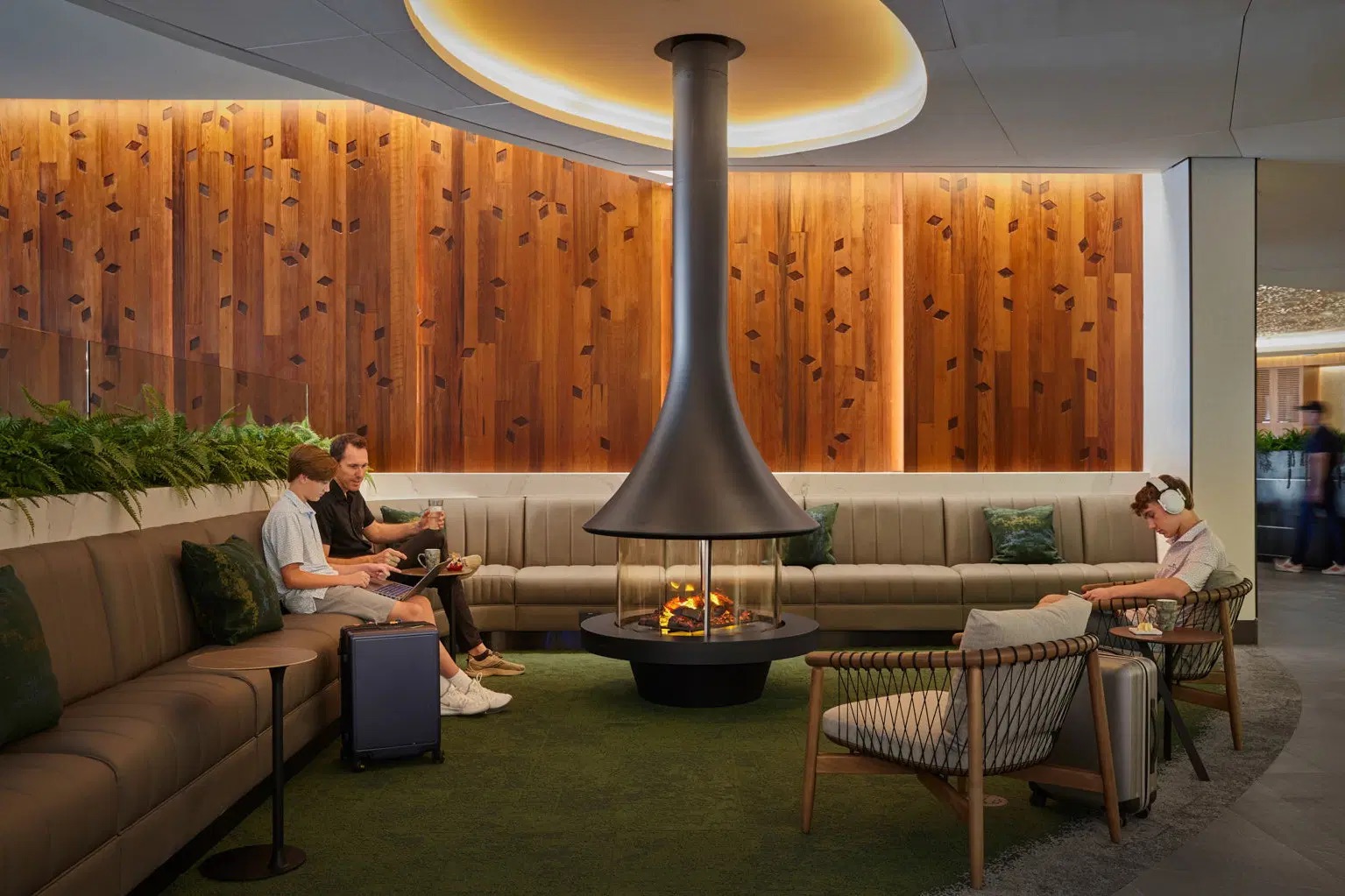 United Club lounge at Newark Liberty Airport with suspended fireplace, wood wall and travelers on sofas