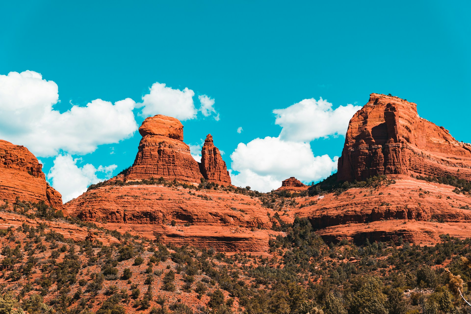 Red rock buttes and formations under a bright blue sky with scattered clouds in Sedona, Arizona