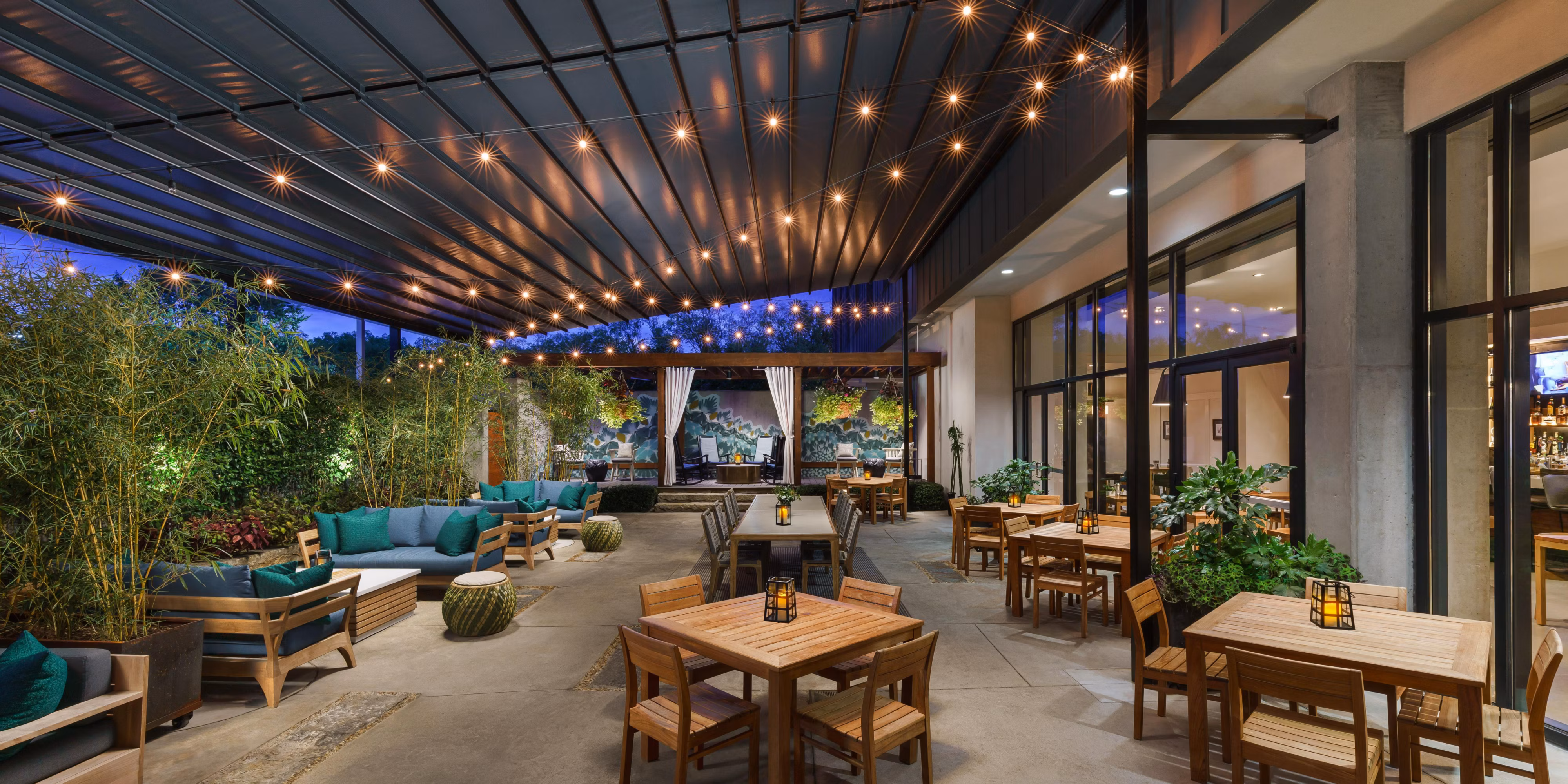 Outdoor hotel patio in Athens, Georgia at dusk with string lights and wooden dining tables
