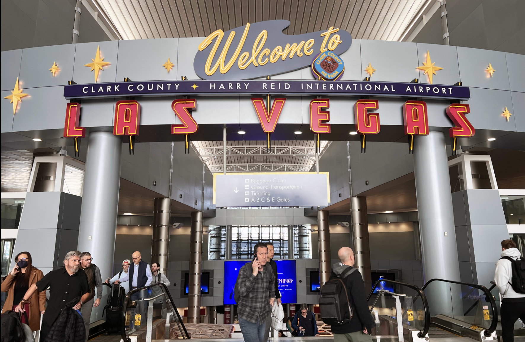 Travelers passing under the Welcome to Las Vegas sign at Harry Reid International Airport