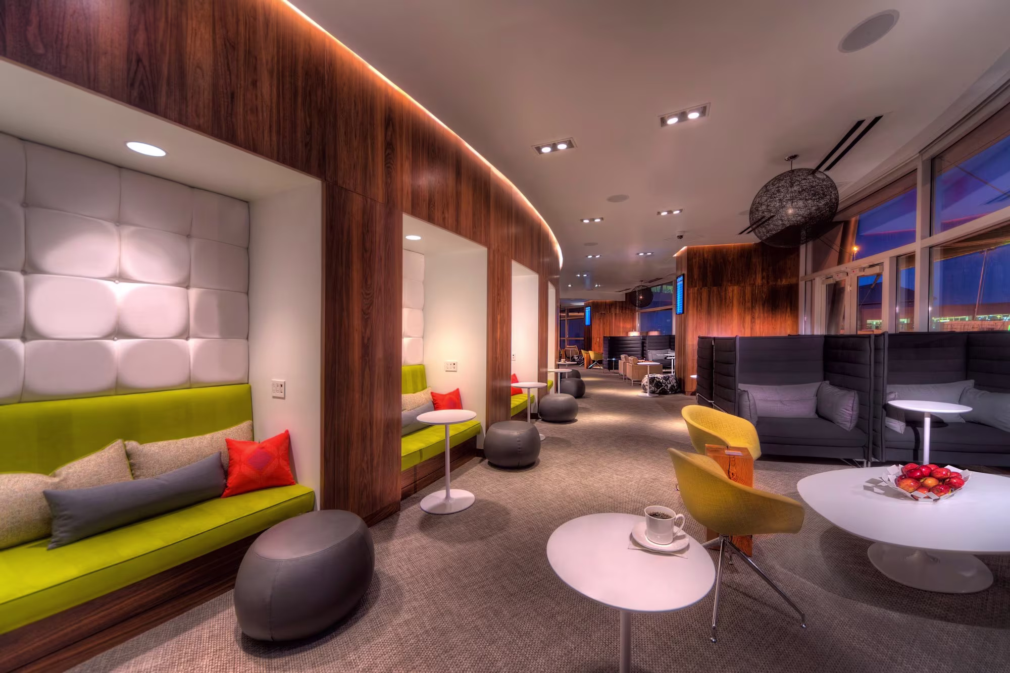Airport lounge seating area with green and grey sofas, side tables and city views at Las Vegas airport