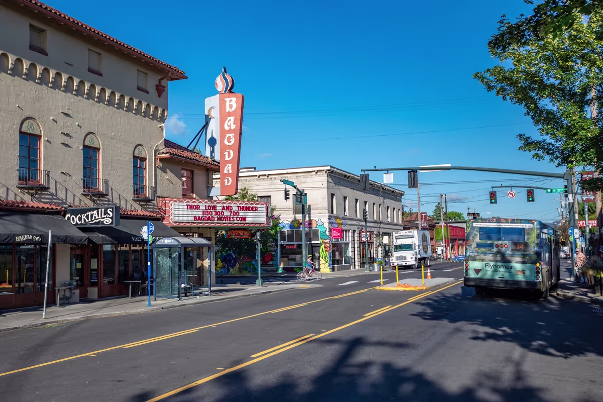 Sunny commercial street with the Bagdad Theater marquee, shops and a bus in Portland's Hawthorne neighborhood
