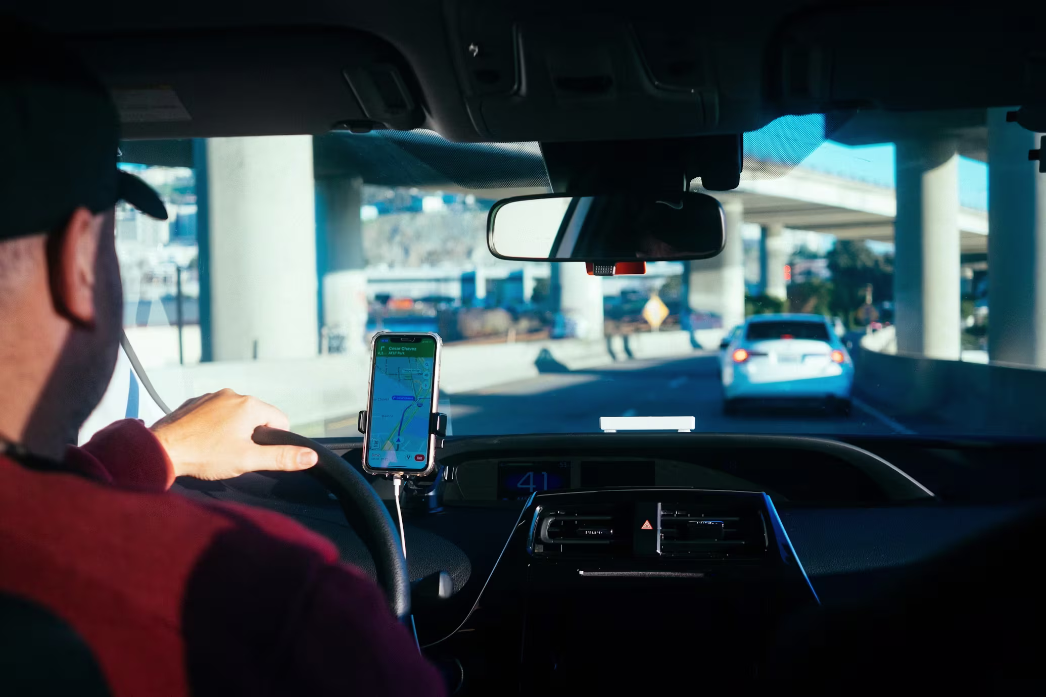 View from inside a rideshare car near the Las Vegas Strip, driver at the wheel with a phone navigation app