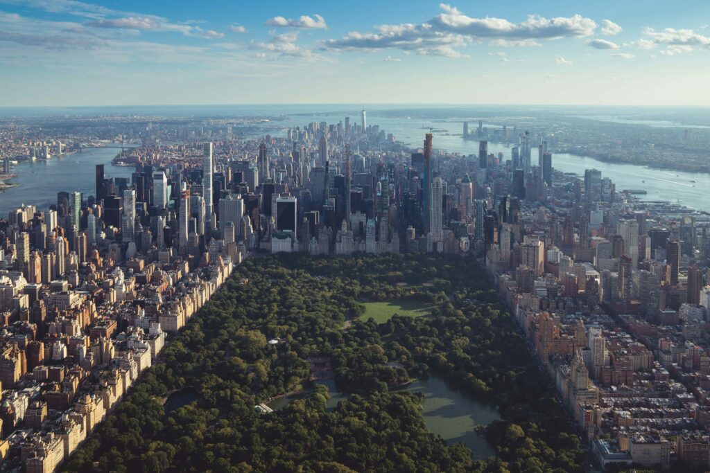Aerial view of Central Park surrounded by skyscrapers in Manhattan, New York City, on a clear day.