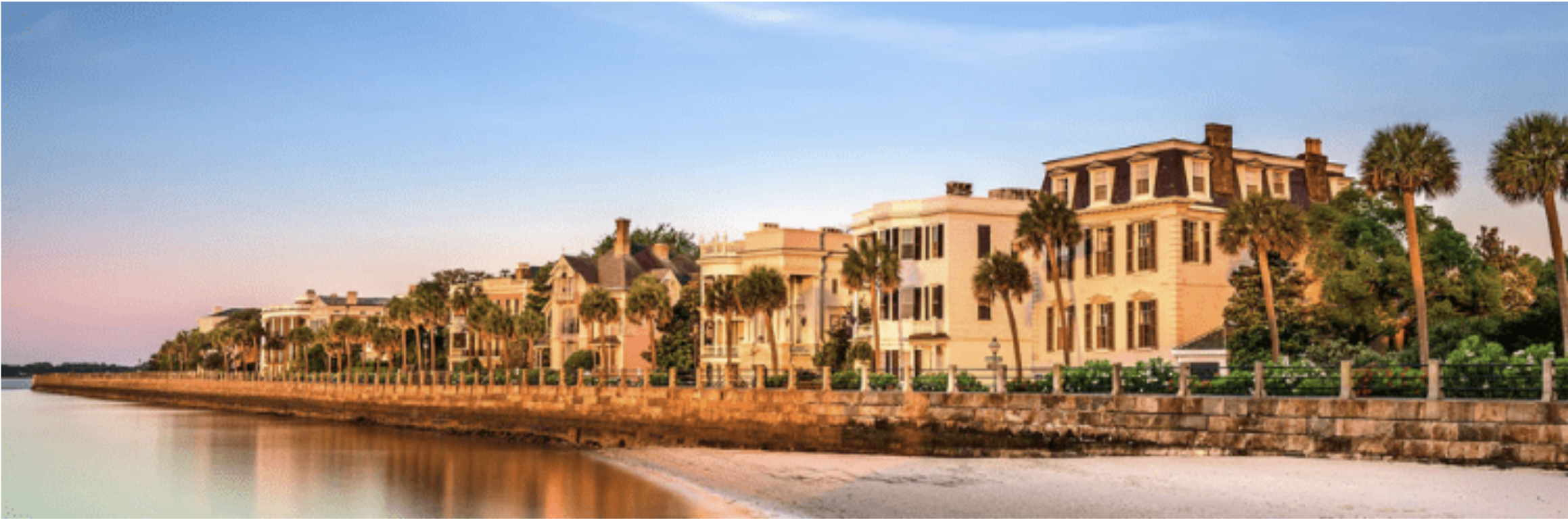 Waterfront row of historic mansions lined with palm trees at sunset