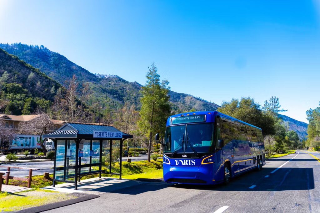 Blue YARTS shuttle bus to Yosemite Valley parked at the Yosemite View Lodge stop with mountains behind