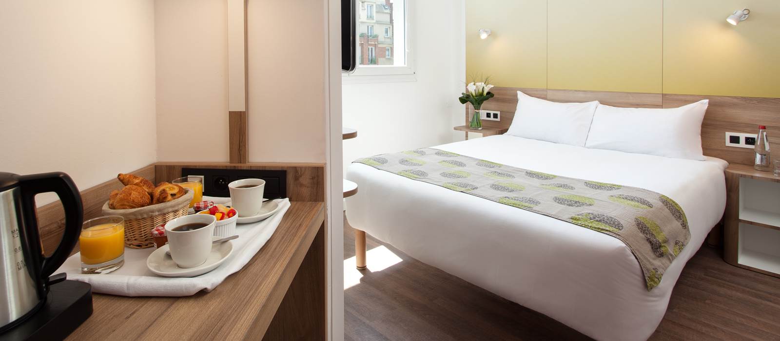Guest room at Motel One Paris-Porte de Versailles with a breakfast tray of pastries, juice and coffee beside a made double bed