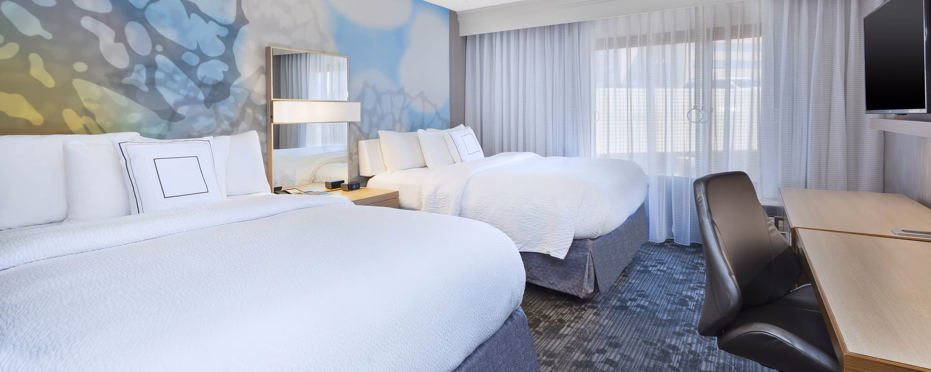 Courtyard guest room near MetLife Stadium with two beds, desk and abstract headboard art
