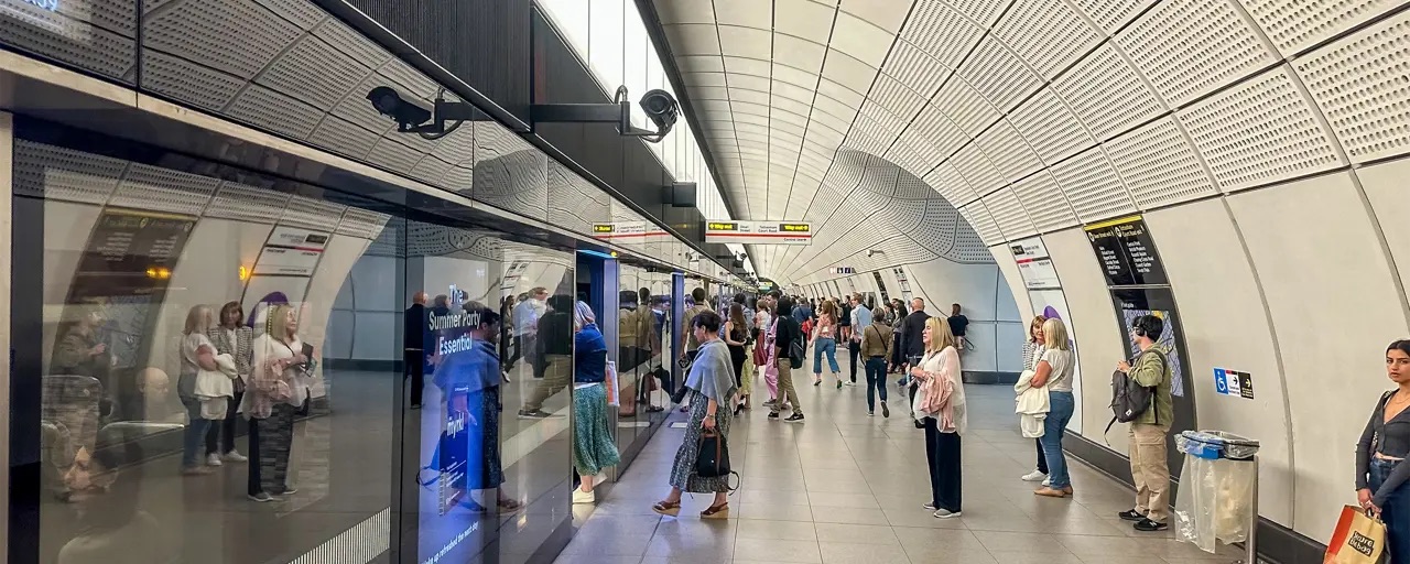Passengers waiting on a modern Elizabeth line platform in London with curved tiled tunnel walls