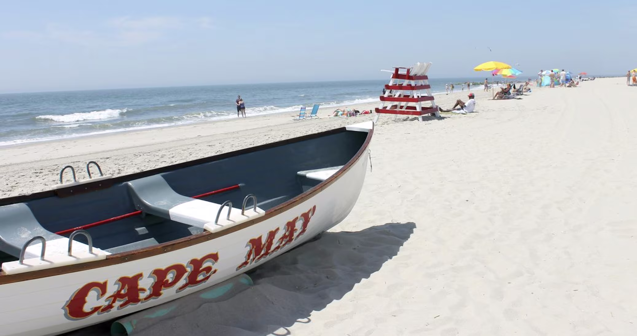 Sandy beach with sunbathers and umbrellas, a popular Memorial Day weekend getaway