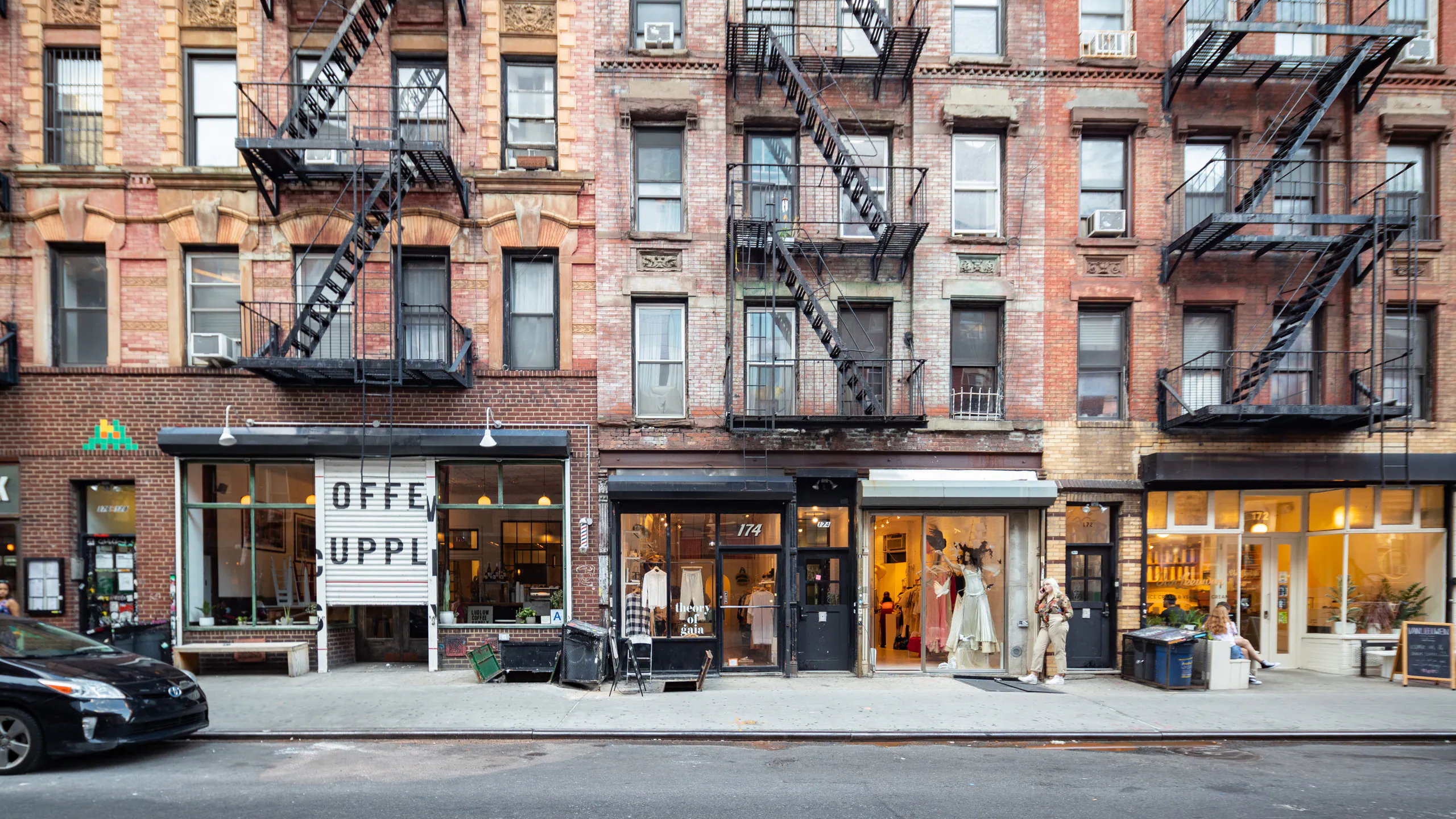 Brick tenement storefronts with vintage and coffee shops along an East Village street in New York