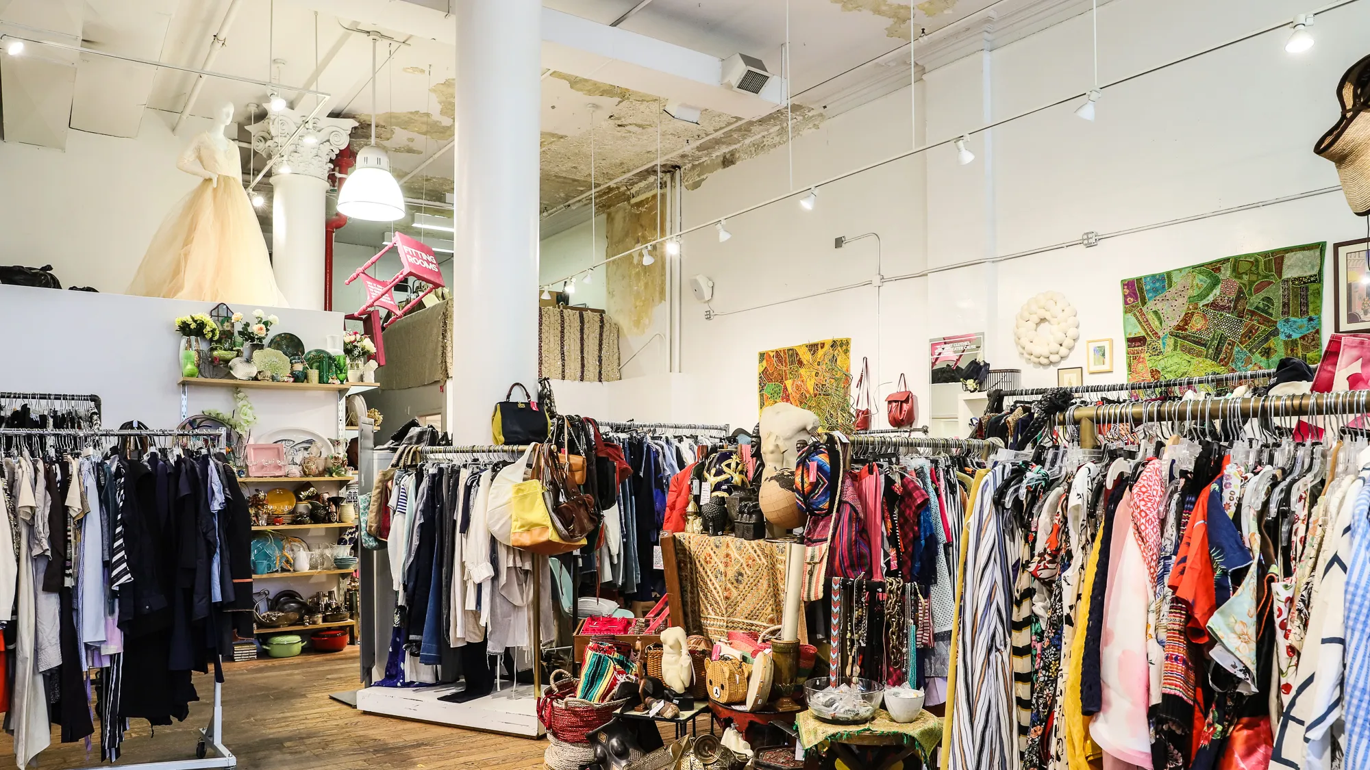 Bright Williamsburg vintage clothing store with racks of secondhand garments and artwork