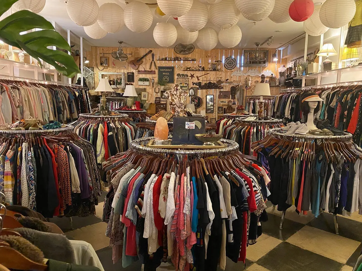 Interior of an East Village thrift shop with circular racks of vintage clothing under paper lanterns