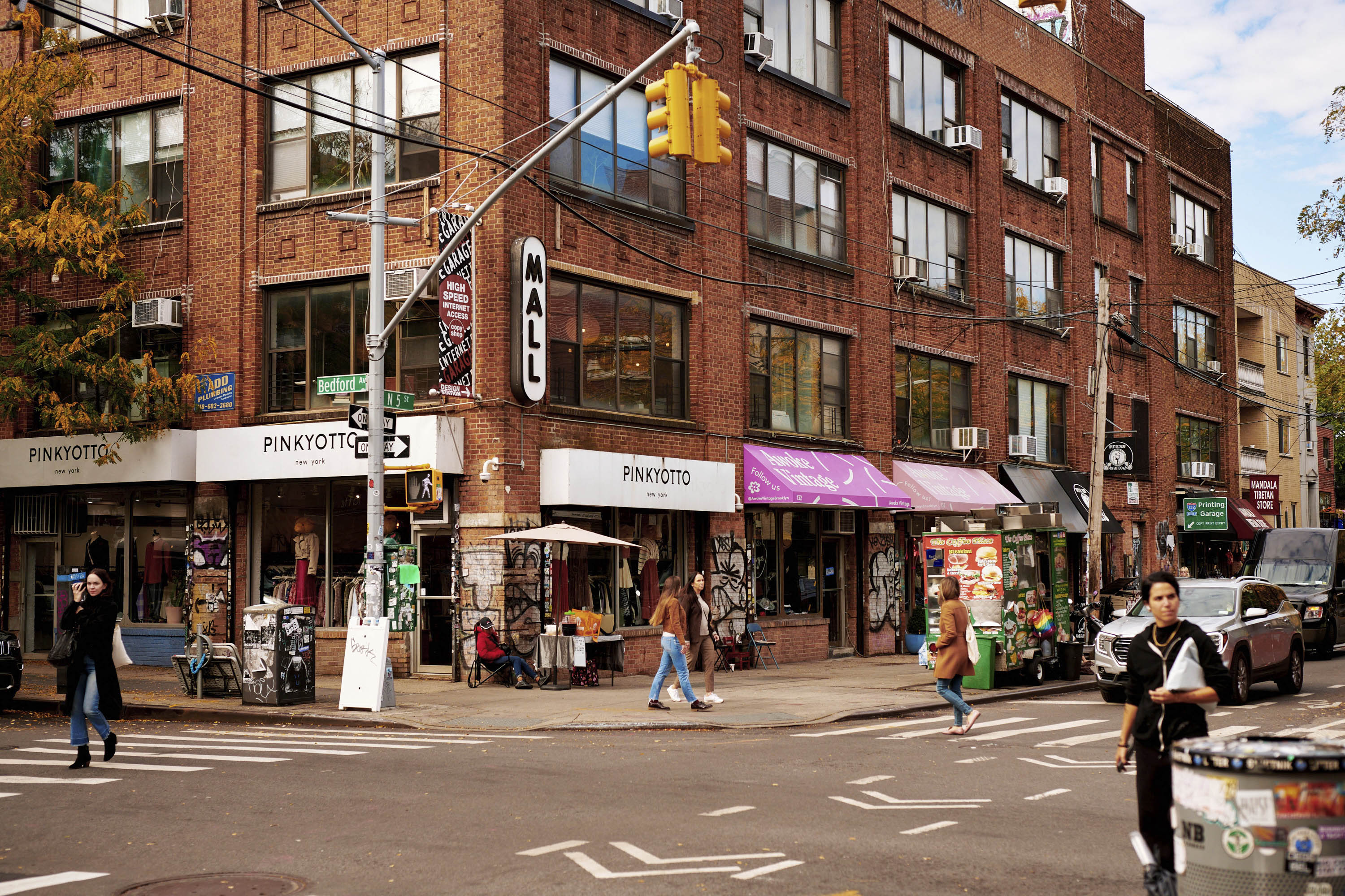 Lower East Side corner with Pinkyotto clothing shops and pedestrians crossing the street in New York