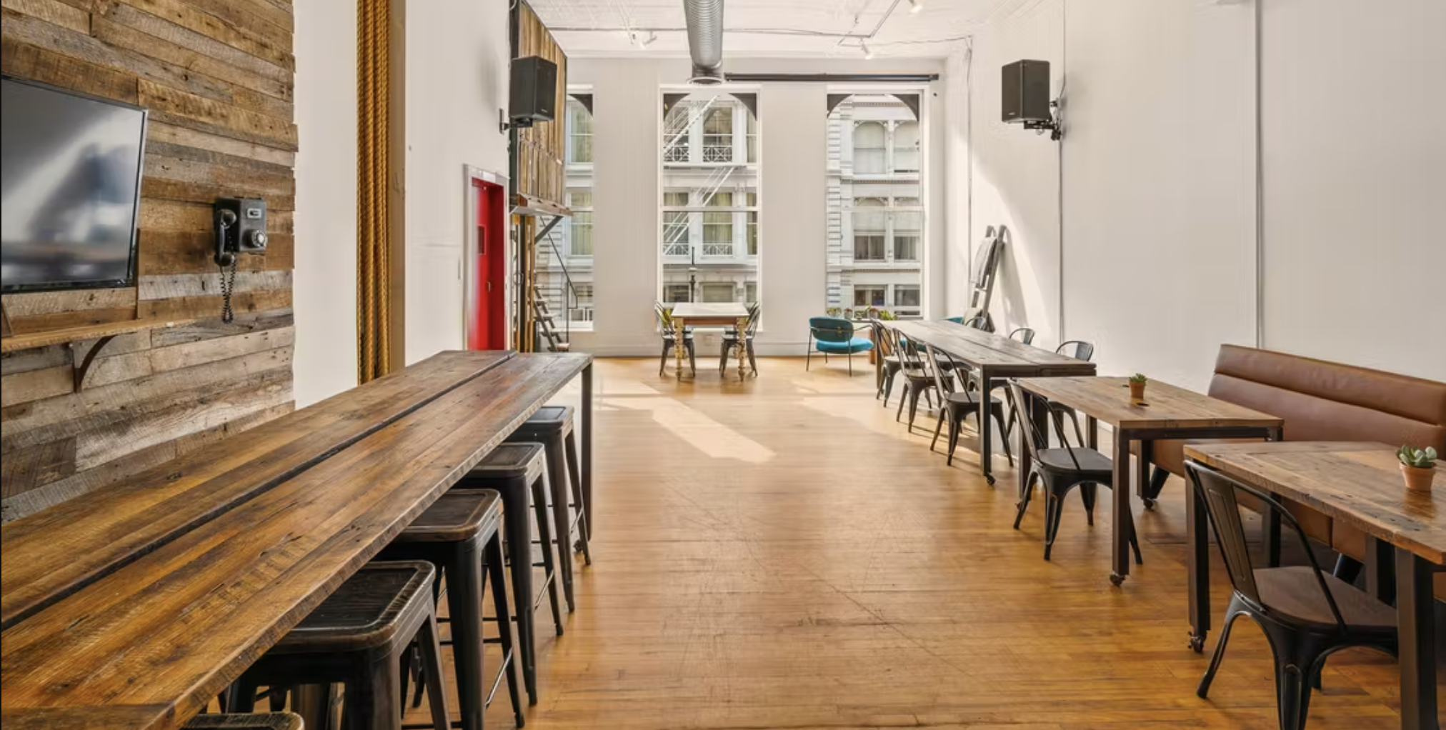 Creative loft coworking space in SoHo or Brooklyn with reclaimed-wood walls, communal high tables, stools and tall windows