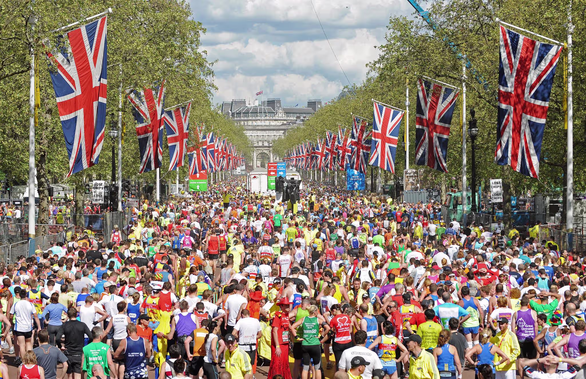 London Marathon runners crowding The Mall toward Admiralty Arch, lined with Union Jack flags on a sunny race day