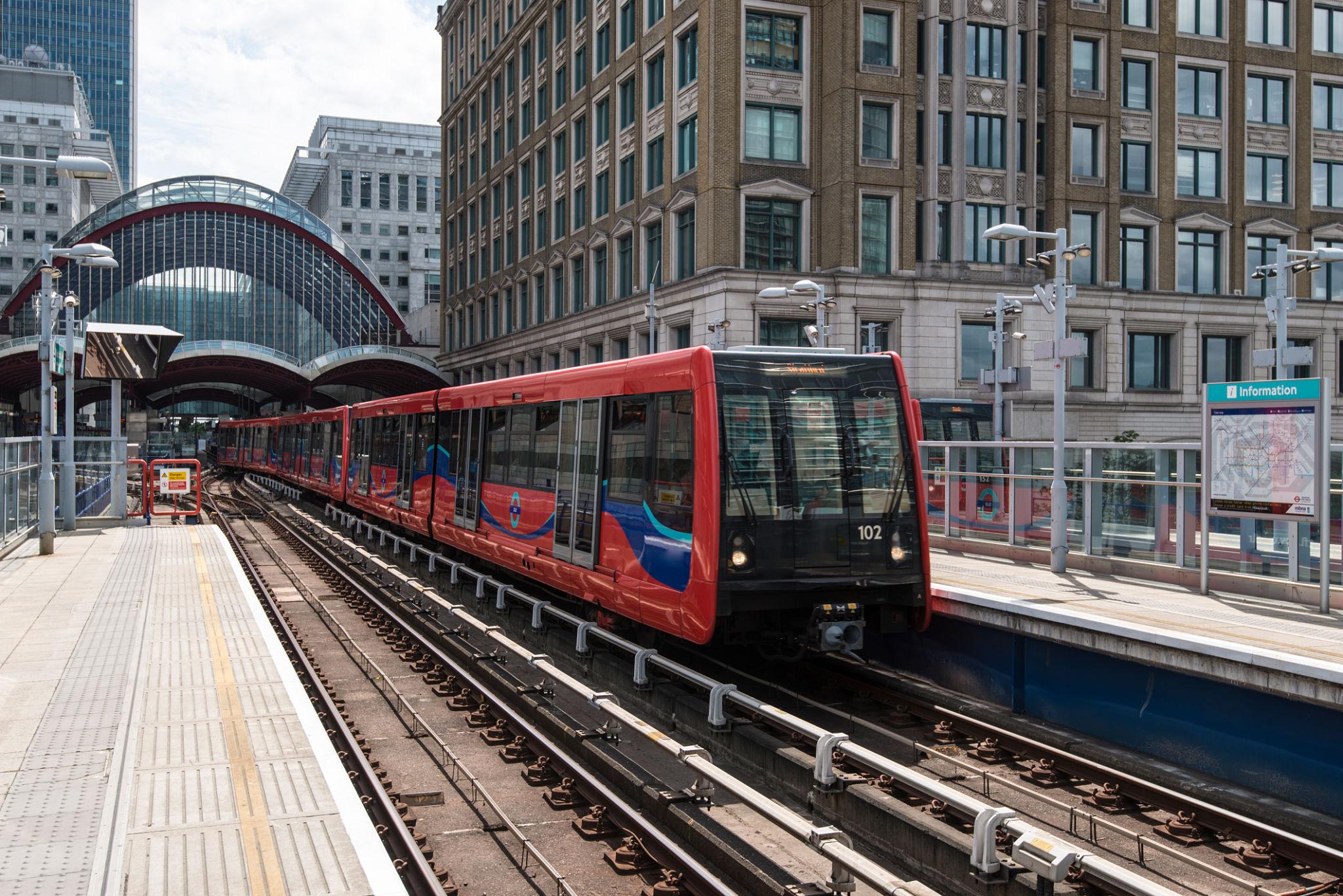 A red Docklands Light Railway train arriving at a Canary Wharf platform, useful for reaching the London Marathon start