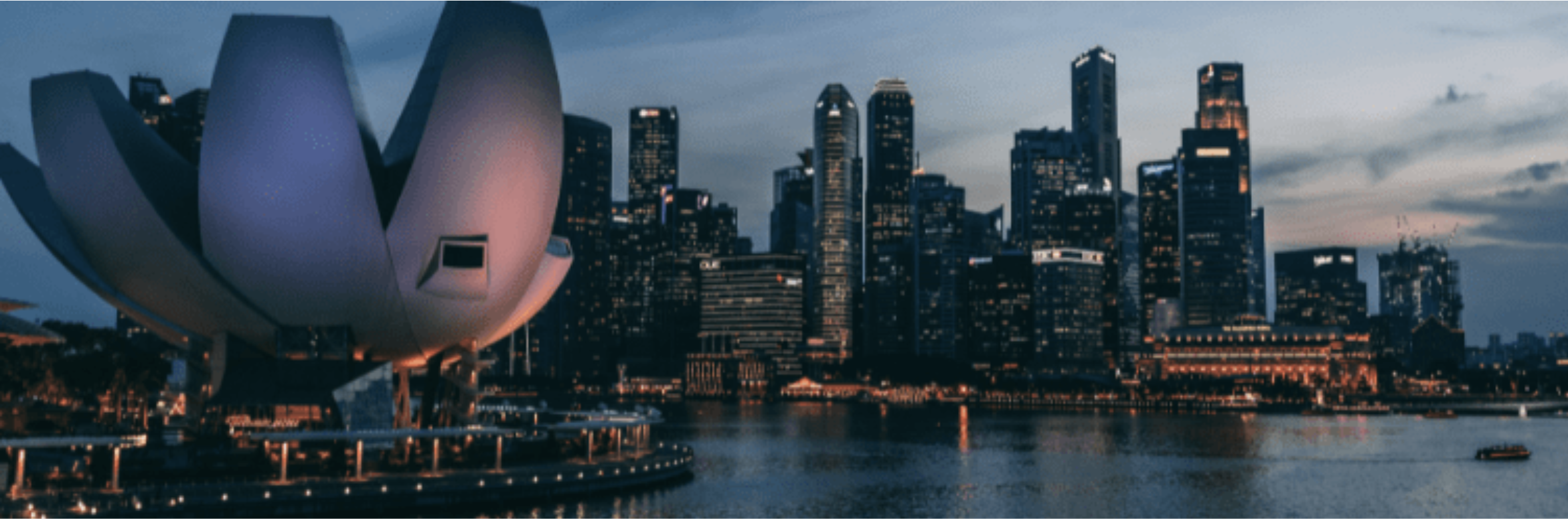 Singapore skyline at dusk with the lotus-shaped ArtScience Museum, illuminated downtown towers and Marina Bay waterfront