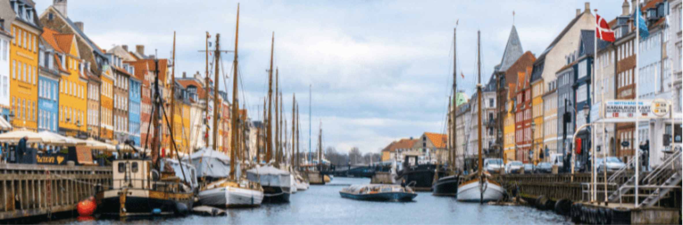 Nyhavn canal in Copenhagen lined with colorful townhouses and moored wooden sailing boats