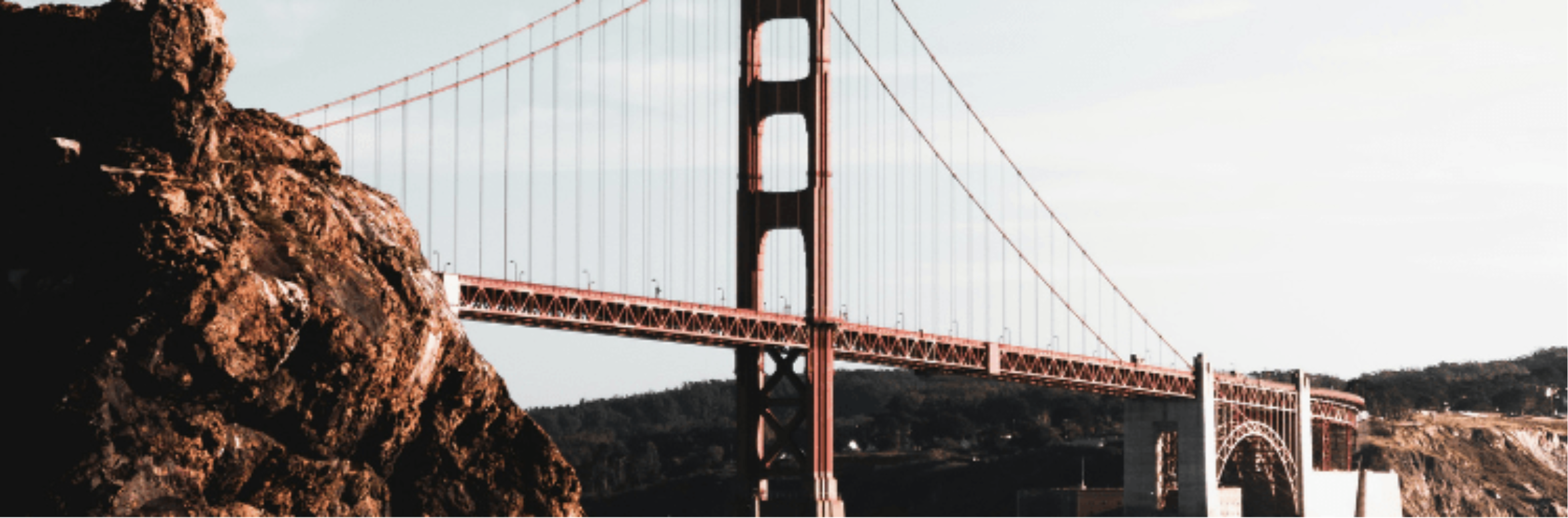 Golden Gate Bridge in San Francisco viewed from the rocky shore with a clear sky over the bay