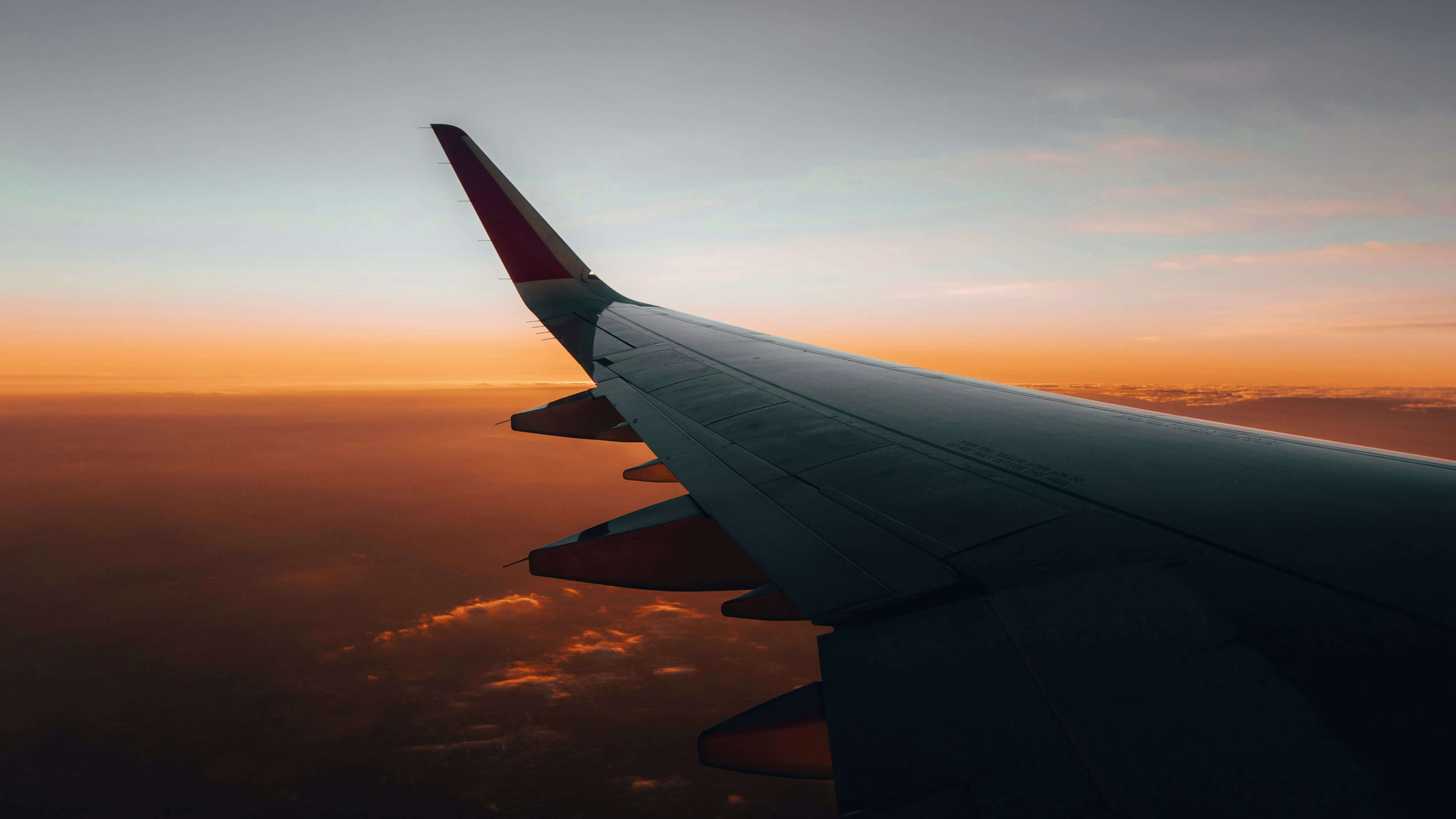 View of an airplane wing above clouds during a flight at sunset
