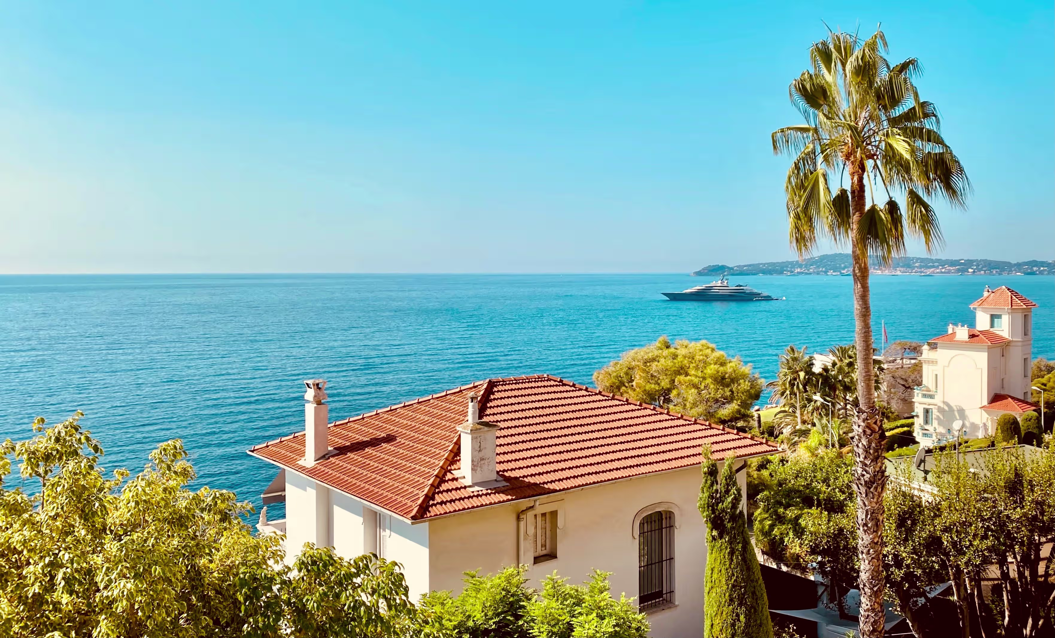 Coastal villa above the Mediterranean near Cap d'Ail and Roquebrune, with a red-tile roof, tall palm tree and sweeping blue sea view