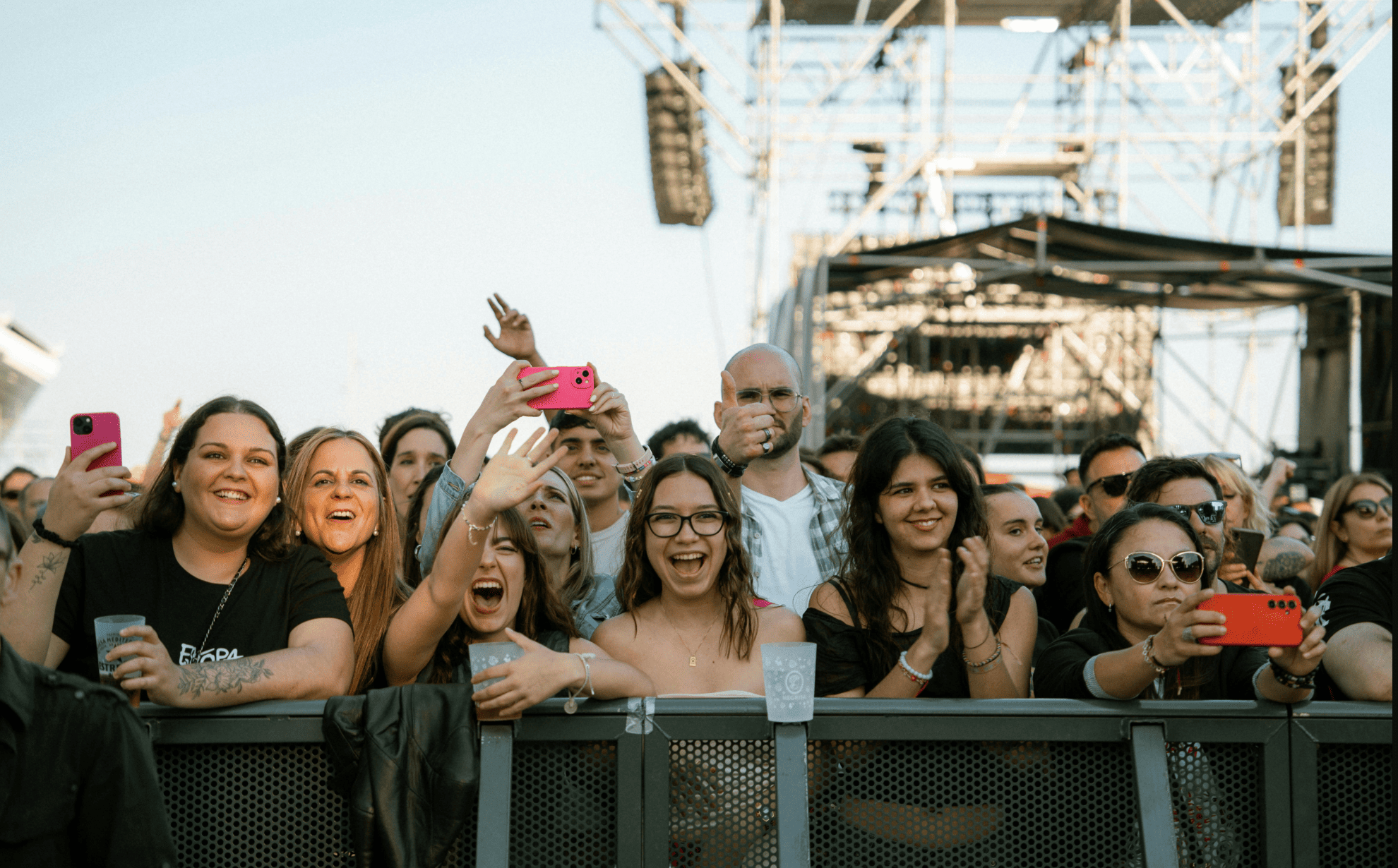 Festival crowd cheering and filming on phones at the front barrier of a Lollapalooza stage in Grant Park, Chicago
