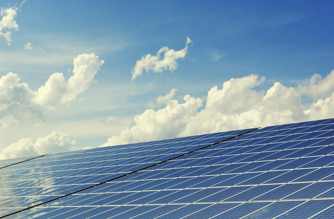 Solar panels under a cloudy blue sky